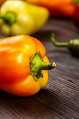 Bulgarian orange pepper with green stems on dark wooden surface