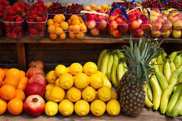 Apples, lemons, oranges, pomegranates, pineapples, peaches and strawberry. Various fruits in a street market