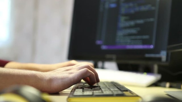 Man programmer writes code using the keyboard. Hands close-up