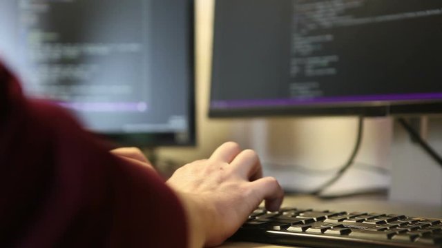 Man programmer writes code using the keyboard. Hands close-up