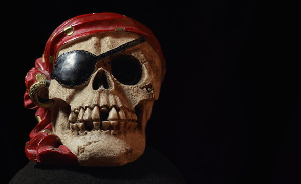 Pirate skull with red head kerchief on dark background.