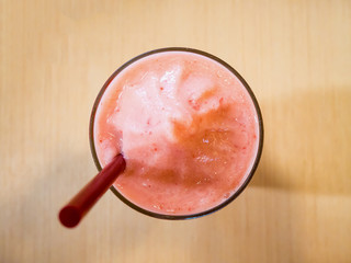 Strawberry smoothie in glass, on wood table