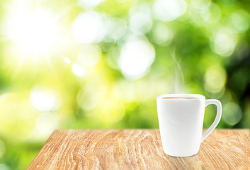 White Coffee cup with hot coffee on wood table at blur green tre