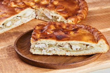 A piece of pie with chicken filling on a wooden plate