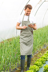 Portrait of an attractive farmer in a greenhouse using tablet