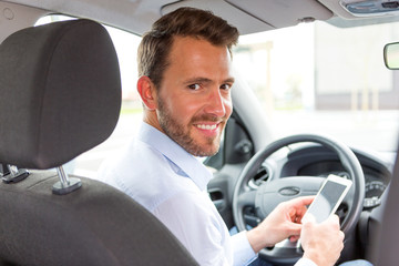 Young attractive man using mobile phone in his car