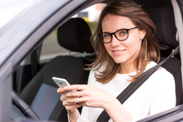 Young attractive woman using mobile phone in his car