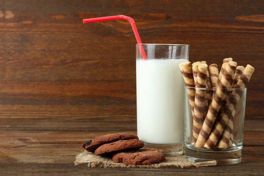a milkshake with a cocktail straw near the glass with cookies on burlap on wooden background