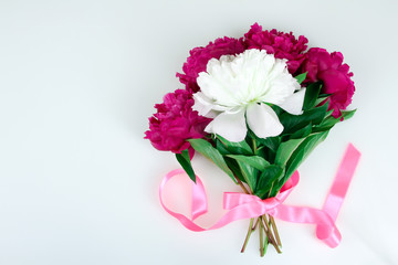a bouquet of red and white peony on a white isolated background tied with pink ribbon