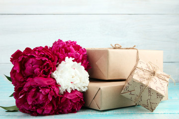 a bouquet of red and white peony on a blue wooden background near the boxes