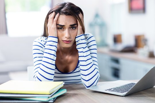 Tensed Woman With Head In Hands Sitting With Laptop