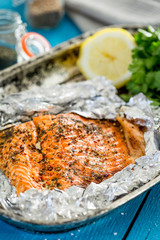 Tasty Baked Fish Salmon in Foil on Blue Table, Close-up
