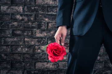 バラの花を持っているスーツの男性