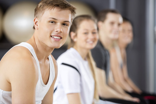 Man Smiling While Sitting With Friends In Gym