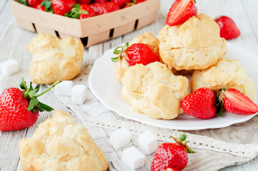
dessert with berries , custard eclairs or cakes with cream and red strawberries on a wooden background