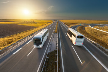 Fast travel buses on the highway at idyllic sunset