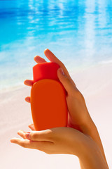 Female hands with suncream bottle background blue heaven