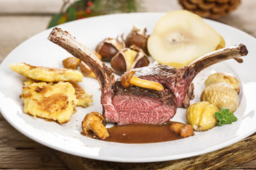 Hirschkarree rosa gebraten auf dem weißen Teller angerichtet mit Maronen und Birne