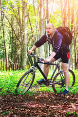 Cyclist with backpack riding the bike, travels in the beautiful summer forest