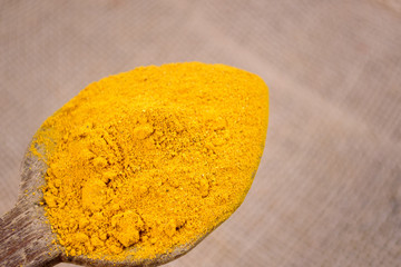 Turmeric powder on wooden spoon. Curcuma
