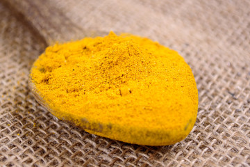 Turmeric powder on wooden spoon. Curcuma