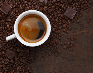 Naklejka premium Coffee cup. Coffee beans and chocolate on a wooden table