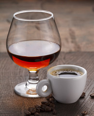 Cup of coffee, cognac glass and coffee beans on a wooden table