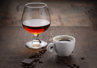 Cup of coffee, cognac glass and coffee beans on a wooden table