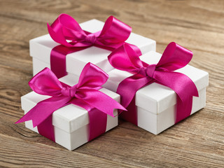 White gift box with violet ribbon on board