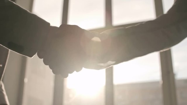Close-up of two businessmen shaking hands in sunlight, backlit shot on Sony NEX 700    