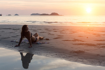 Young beautiful woman lying on the beach during sunset.