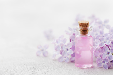 Glass jar with rose water and lilac flowers for spa and aromatherapy, copy space for text