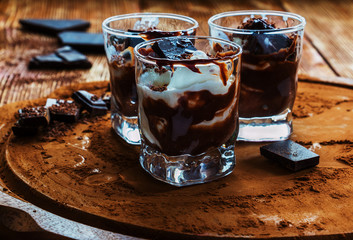 Ice cream with chocolate in small glasses on cocoa background.