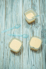 Three jars of yogurt stands on the aged boards