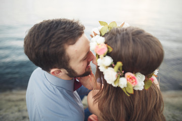 Naklejka premium Wedding couple kissing and hugging on rocks near blue sea
