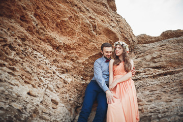 Fototapeta premium Romantic loving couple walking on the beach with rocks and stones