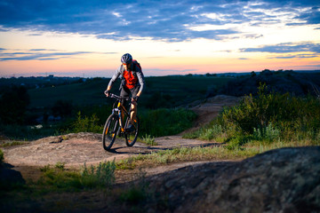 Fototapeta na wymiar Cyclist Riding the Bike on Mountain Rocky Trail at Sunset