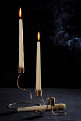 A set of hand-made candlesticks made of metal. On a black background. tall candles