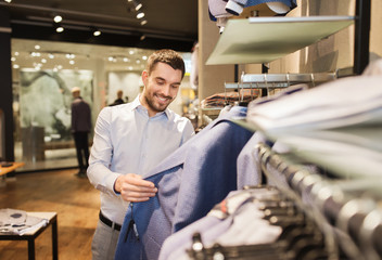happy young man choosing clothes in clothing store