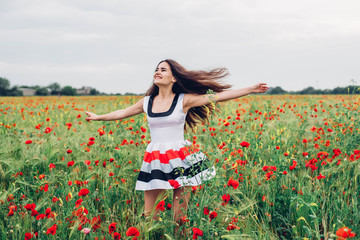 Obraz na płótnie Canvas young beautiful woman having fun in poppy field 