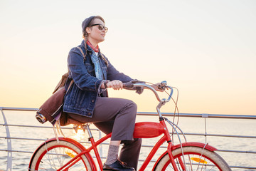 woman riding red vintage bicycle on seaside during sunset or sunrise 