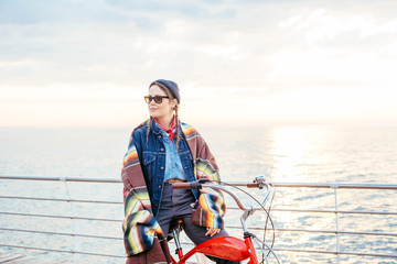 woman riding red vintage bicycle on seaside during sunset or sunrise 