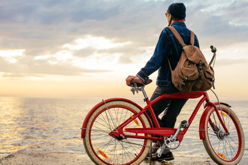 Fototapeta premium woman with vintage bicycle looking at view on seaside during sunset or sunrise