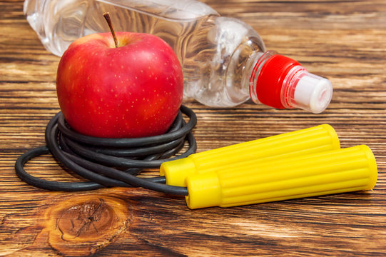 Apple with jump rope and bottle of water on the table