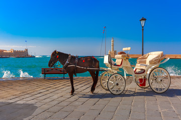 Horse carriage and Lighthouse in old harbour of Chania on a summer sunny day, Crete, Greece