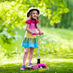 Little girl riding a colorful scooter