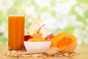 Pumpkin puree, seeds, glass  juice, apples  on abstract green background.