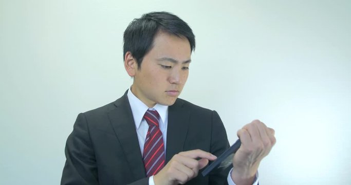 Japanese young business man calculating costs confused face 