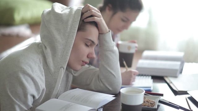  Tired male student in hoodies falls asleep.
