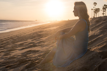 Beautiful female musician at the beach with her guitar. 
